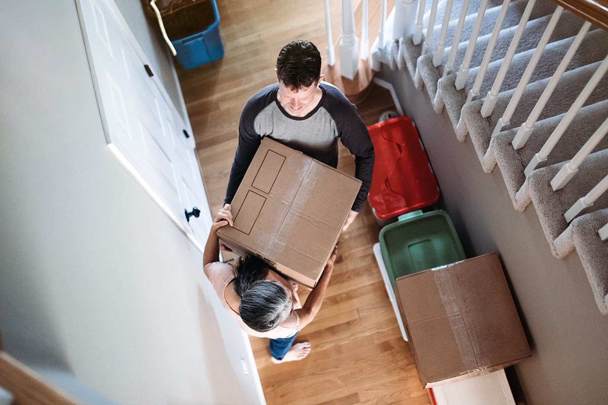 A couple moving a box through the hallway of their home. 